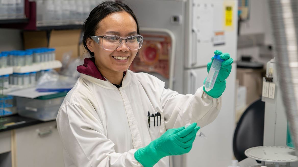 Description A researcher holds up two tubes with a liquid sample