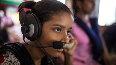 Girl listens to audio from computer inside Child Resource Centre Mumbai, India.